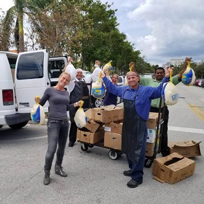 postirma2.jpg Volunteers holding bags of turkeys standing outside near parked trucks