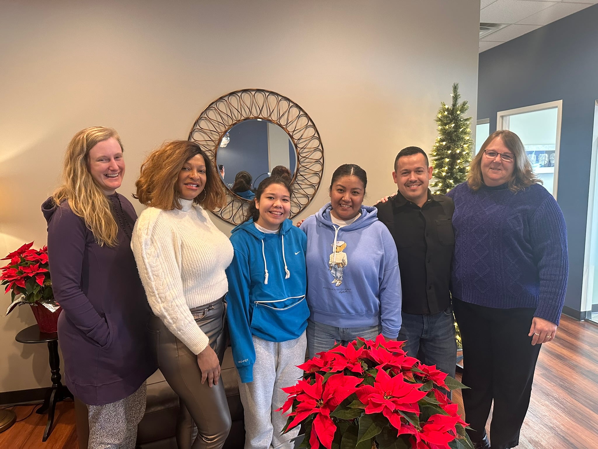 Elizabeth and the crew that helped her get ready for homeownership stand near a festive poinsettia. 