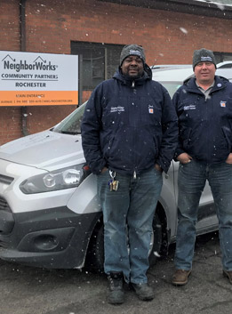 Two NeighborWorks Community Partners staff members stand in front of a white truck in the snow