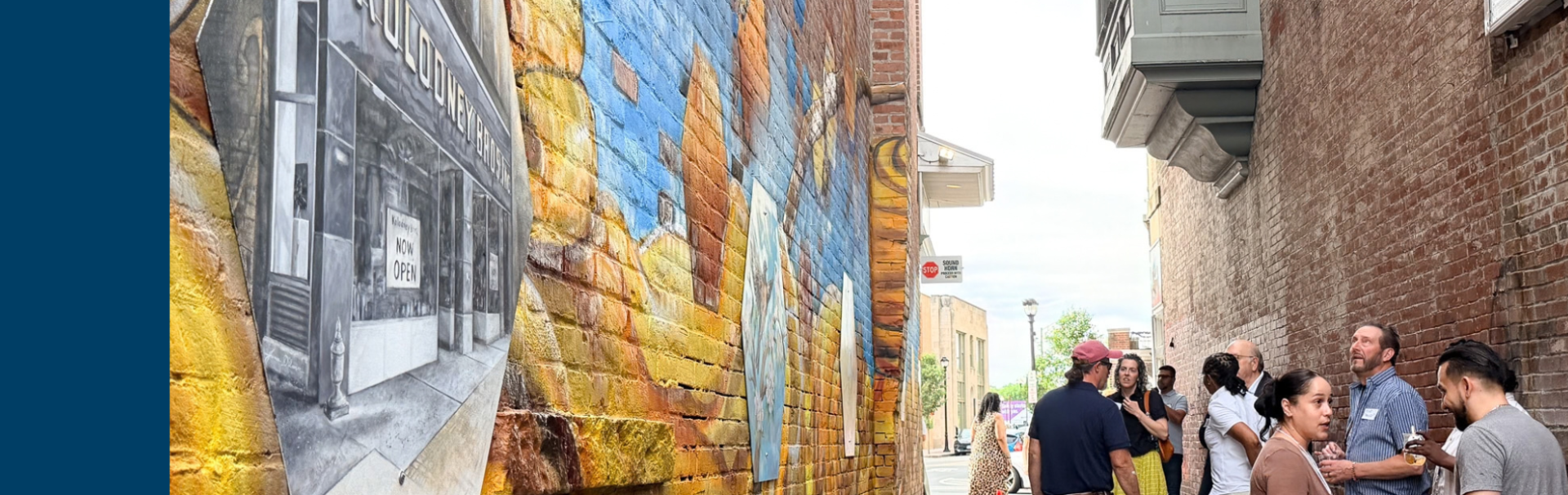 A mural on the wall near the gallery in Rhode Island with lots of gold and many onlookers.