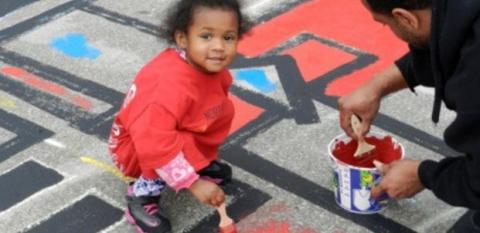 A girl helps her father paint during a previous NeighborWorks Week.