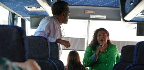 Talking during a bus tour, a woman explains the importance of nonprofits in helping small businesses. 